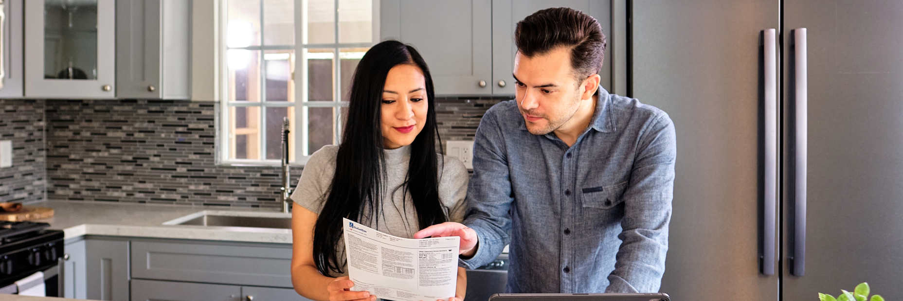 A couple looking at their utility bill in their kitchen